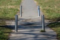 Rarely used old paved path with cracked asphalt and four broken damaged shiny metal protective poles Royalty Free Stock Photo