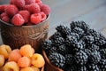 Raspberries are black, yellow and red in clay ware on a wooden table.n Royalty Free Stock Photo