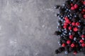 Raspberries, blackberries, blueberries a gray abstract background.