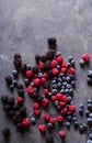 Raspberries, blackberries, blueberries a gray abstract background.