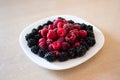 Raspberries and blackberries on the white plate