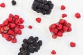 Raspberries and blackberries white wooden background