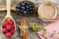 Raspberries and blueberries in spoons with pink napkin and a jar of honey with cinnamon on wooden background. Healthy eating Royalty Free Stock Photo