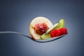 Raspberries, peach and kiwi on curved spoon