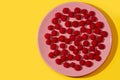 Raspberries on a pink plate on a yellow background. Royalty Free Stock Photo