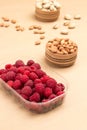 Raspberries in plastic container. Almonds in wooden box Royalty Free Stock Photo