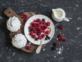 Raspberries, red and blackcurrants, a meringue, cream on a rustic cutting board Royalty Free Stock Photo