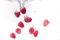 Raspberries splashing into crystal clear water with air bubbles Royalty Free Stock Photo