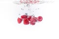 Raspberries splashing into crystal clear water with air bubbles Royalty Free Stock Photo