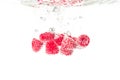 Raspberries splashing into crystal clear water with air bubbles Royalty Free Stock Photo