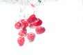 Raspberries splashing into crystal clear water with air bubbles Royalty Free Stock Photo