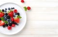 raspberries, strawberries, blackberries, wild strawberries, blueberries on white plate on white wooden table for food card design Royalty Free Stock Photo