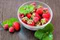 Raspberries with strawberries in a bowl on a brown wooden table with mint leaves Royalty Free Stock Photo