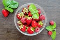 Raspberries with strawberries in a bowl on a brown wooden table with mint leaves Royalty Free Stock Photo