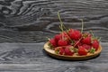 Raspberries with tails lie on a wooden saucer. On black boards, with an expressive woody texture