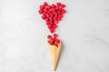 Raspberries in waffle ice cream cone and heart made of berries on white marble background. Fresh summer berries Royalty Free Stock Photo