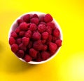 Raspberries in a white plate on a yellow background Royalty Free Stock Photo