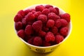 Raspberries in a white plate on a yellow background Royalty Free Stock Photo