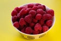 Raspberries in a white plate on a yellow background Royalty Free Stock Photo