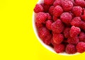 Raspberries in a white plate on a yellow background Royalty Free Stock Photo