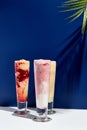 Raspberry and banana, pineapple, strawberry and coconut milk smoothie over white and blue background. Palm leaf with sunshine and Royalty Free Stock Photo