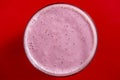 Raspberry banana smoothie in glass on a red background, closeup, top view Royalty Free Stock Photo