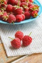Raspberry in blue dish and in front of white fabric on old v Royalty Free Stock Photo