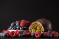Raspberry and blueberry with a passionfruit, on dark background, front view, horizontal image, a lot of free space, room for text Royalty Free Stock Photo