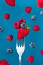 Raspberry, blueberry and strawberry on fork against berries blue background. Healthy eating concept. Summer food Royalty Free Stock Photo