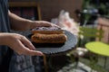 Raspberry and caramel eclair on round black rock stand in hands. Sweets to order concept. Two eclairs with white and