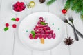 Raspberry Christmas tree on a white plate with white chocolate and icing sugar.