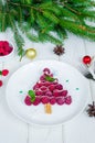 Raspberry Christmas tree on a white plate with white chocolate and icing sugar.