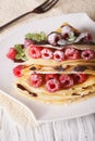 Raspberry crepes with chocolate close-up on a plate. vertical