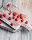 Raspberry fruits on old cutting board, healthy pile of summer berries on grey wooden background Royalty Free Stock Photo