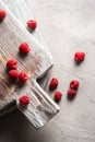 Raspberry fruits on old wooden cutting board, healthy pile of summer berries on stone concrete background Royalty Free Stock Photo