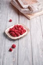 Raspberry fruits in plate near to old cutting boards, healthy pile of summer berries on grey wooden background Royalty Free Stock Photo