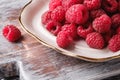 Raspberry fruits in plate on old cutting board, healthy pile of summer berries on grey wooden background Royalty Free Stock Photo