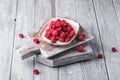 Raspberry fruits in plate on old cutting board, healthy pile of summer berries on grey wooden background Royalty Free Stock Photo