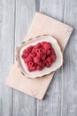 Raspberry fruits in plate on old cutting board, healthy pile of summer berries on grey wooden background Royalty Free Stock Photo