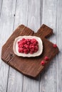 Raspberry fruits in plate on old teak cutting board, healthy pile of summer berries on wooden background Royalty Free Stock Photo