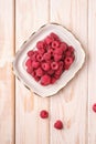 Raspberry fruits in white plate, healthy pile of summer berries on wooden background Royalty Free Stock Photo