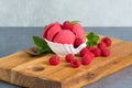 Raspberry ice cream sorbet in white porcelaine bowl with raspberry, mint leaves copy space on wooden plank and grey textured Royalty Free Stock Photo