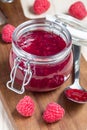 Raspberry jam in glass jar on a wooden board, vertical Royalty Free Stock Photo