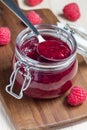 Raspberry jam in glass jar on a wooden board, vertical Royalty Free Stock Photo