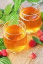 Raspberry leaf tea in glass cups with leaves and berry on rustic background