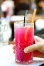 Raspberry lemonade. Hand holding a glass of raspberry ice tea with lemon and ice cubes. Cold refreshing pink cocktail in a high Royalty Free Stock Photo