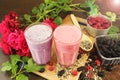 Raspberry milkshake and silky milkshake at home. On a wooden dark brown table, there are two glasses of cocktails and a bowl with Royalty Free Stock Photo