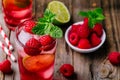 Raspberry Mojito Lemonade with lime and fresh mint in glass on wooden background