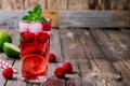 Raspberry Mojito Lemonade with lime and fresh mint in glass on wooden background Royalty Free Stock Photo