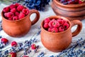 raspberry in pottery cup with lavander on wooden background